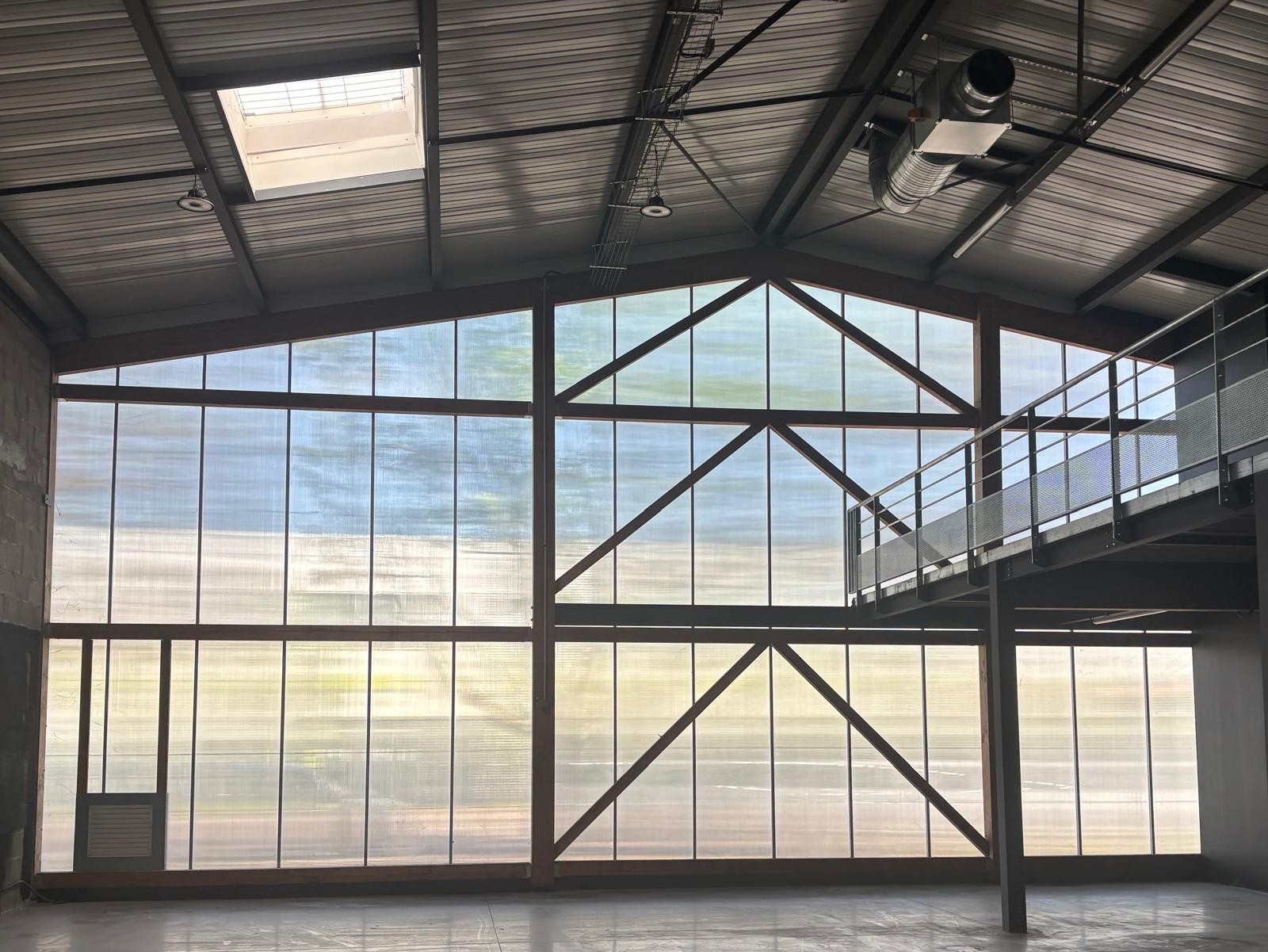 Intérieur de l'atelier Atelier Point Final : grande façade vitrée et charpente métallique