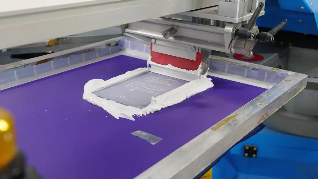 Atelier de sérigraphie : raclette déposant l'encre sur l'écran textile